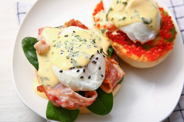 Plate with tasty eggs Benedict on white wooden table, closeup