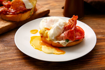 Plate with tasty egg Benedict on wooden table, closeup