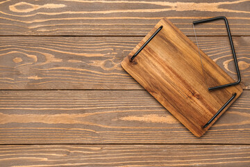 Cutting board with cheese slicer on wooden background