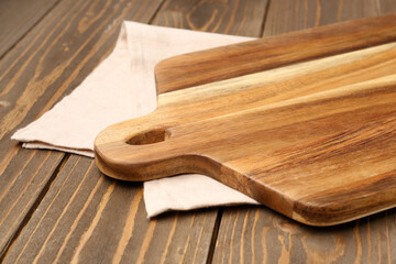 Cutting board and napkin on wooden background, closeup