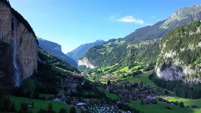 Stunning aerial view: Peaceful Lauterbrunnen Valley Village on a sunny summer day ,Between Swiss Pine trees snow covered alp Mountains, fresh green meadows, and Staaubbach waterfall.