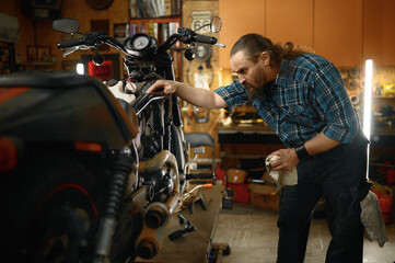 Bearded man biker working in motorbike repair shop on weekend