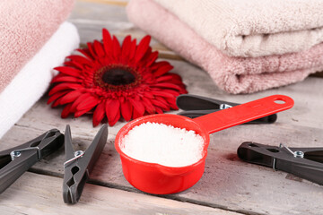 Laundry detergent, clothespins, gerbera flower and folded towels on wooden background