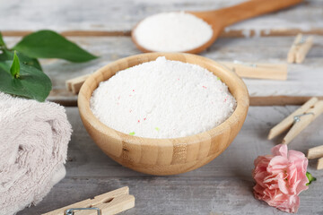 Laundry detergents, clothespins and carnation flower on wooden background