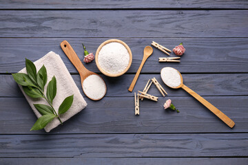 Laundry detergents, clothespins, carnation flowers and plant branch on grey wooden background