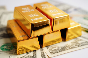 Gold bars on US dollar banknote money, finance trading investment business currency concept.