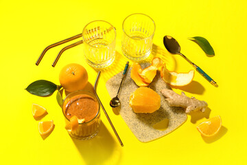 Composition with glass of healthy orange smoothie and ingredients on yellow background