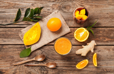 Composition with glass of healthy orange smoothie and ingredients on wooden table