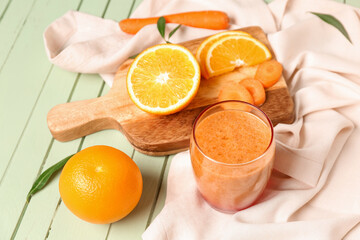 Glass of healthy orange smoothie and ingredients on green wooden table