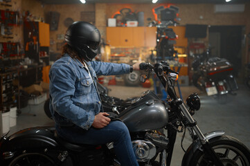 Biker in protective helmet sitting on motorcycle testing new vehicle