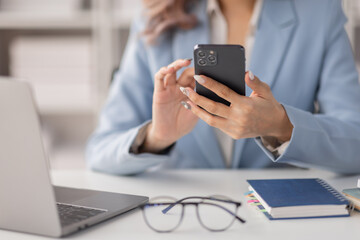 Asian women hold smartphone and use pc at the workplace. Project stats financial data sales charts on laptop and cellphone
