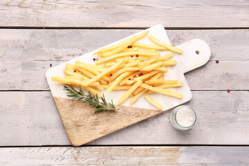 Board with tasty french fries and salt on wooden background