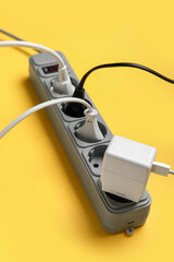Electric extension cord with plugs on yellow background
