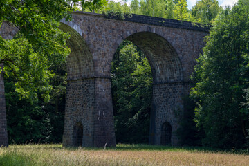 old railway viaduct arches made of irregular hewn stone in the forest