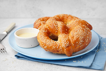 Plate with tasty pretzels and condensed milk on light background, closeup