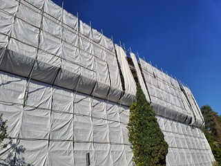 House building Italy, construction restoration or maintenance site with scaffolding and protective...