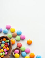 Sweet Easter concept. Colorful and chocolate easter eggs with sweet dragee on white background with copy space. Design for a greeting card for the Easter holiday. Flat lay. Preparation for holiday.