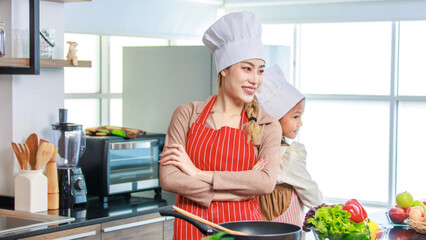 Asian young cheerful female mother and little cute girl daughter wearing white tall cook hat and...