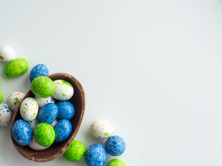 Sweet Easter concept. Blue, white and green chocolate easter eggs with sweets on white background with copy space. Design for a greeting card for the Easter holiday. Flat lay. Preparation for holiday
