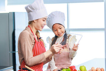 Asian young female chef housewife mother wears white tall cook hat and apron showing mockup glass...