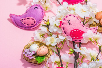Obraz na płótnie Canvas Gentle Easter composition with cherry flowers and handmade felt birds. Decorative eggs and nest