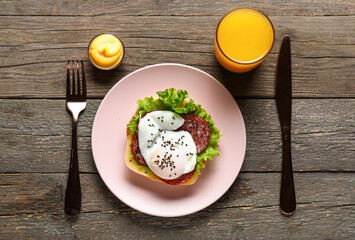 Plate with tasty egg Benedict and glass of orange juice on wooden background