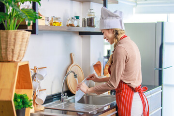 Millennial Asian young cheerful female housewife chef wearing white tall cook hat and apron...