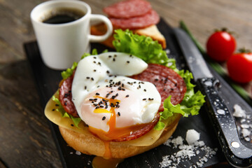 Board with tasty egg Benedict on wooden background