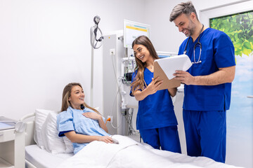 Doctors in uniform with stethoscope using clipboard standing in hospital ward with patient resting...