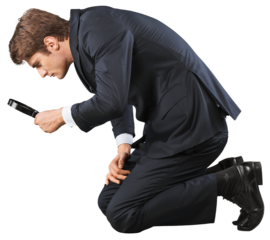 Businessman looking through magnifying glass standing on knees isolated on white