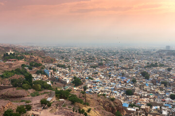 Naklejka premium Top view of Jodhpur city as seen from famous Mehrangarh fort, Jodhpur, Rajasthan, India. Orange sky in the background. Mehrangarh Fort is UNESCO world heritage site popular amongst tourists worldwide.