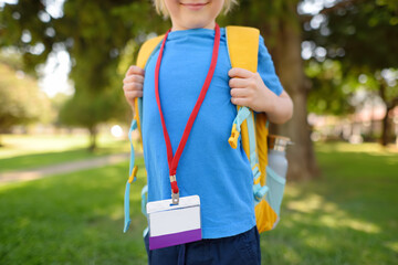 Child with name badge on neck goes to school. Icon has white blank card for copy of text. This is student identification label with an empty ID card layout.