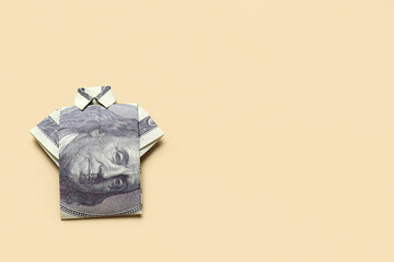 Origami t-shirt made of dollar banknotes on beige background