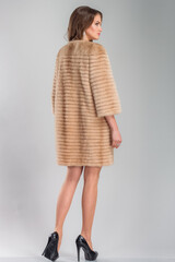 A beautiful young woman of European complexion wearing a fur coat, studio photoshoot