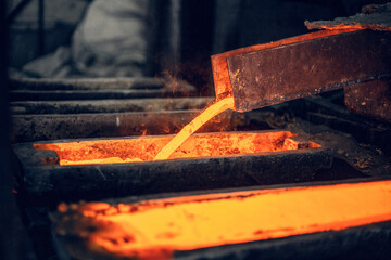 red-hot brass melt pours into the mold in a foundry