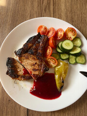 Grilled steak with vegetables and sauce on a plate.