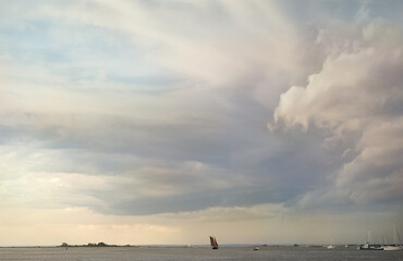 Fototapeta na wymiar sailboat on the horizon of coastal waters with passing storm clouds above