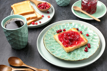 Tasty toast with cranberry jam and cup of coffee on dark background