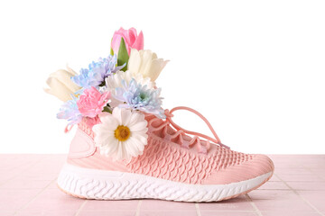 Sneaker with spring flowers on table against white background