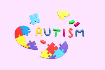 Word AUTISM with puzzle pieces on lilac background
