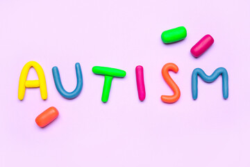 Word AUTISM made of plasticine on lilac background