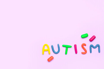 Word AUTISM made of plasticine on lilac background