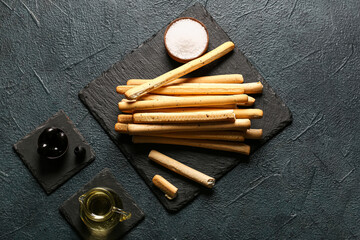 Slate board with tasty Italian Grissini on dark background