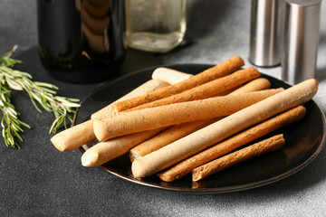 Plate with tasty Italian Grissini on grunge background