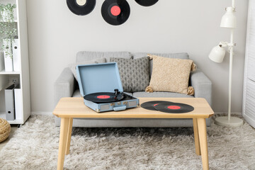 Record player with vinyl disks on table in interior of living room