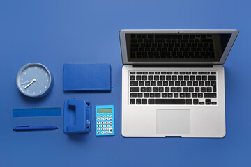 Composition with laptop, calculator and clock on blue background