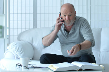  old man with book talking on phone and taking notes