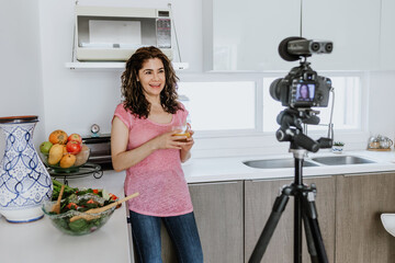 Latin woman influencer recording video class or live stream with camera about healthy eating and...