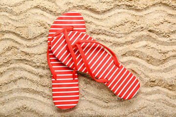 Red flip-flops on sand, top view
