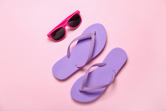 Flip-flops with sunglasses on pink background